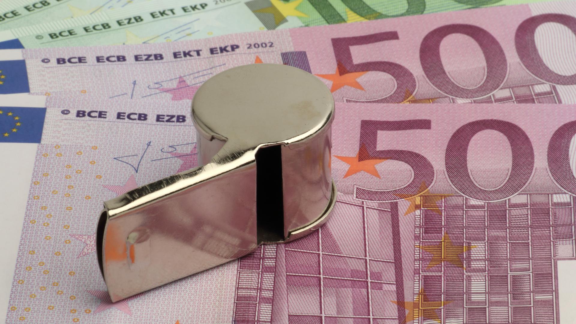 Eine Trillerpfeife liegt auf mehreren 500-Euro-Scheinen. Eine Trillerpfeife liegt auf mehreren 500-Euro-Scheinen.