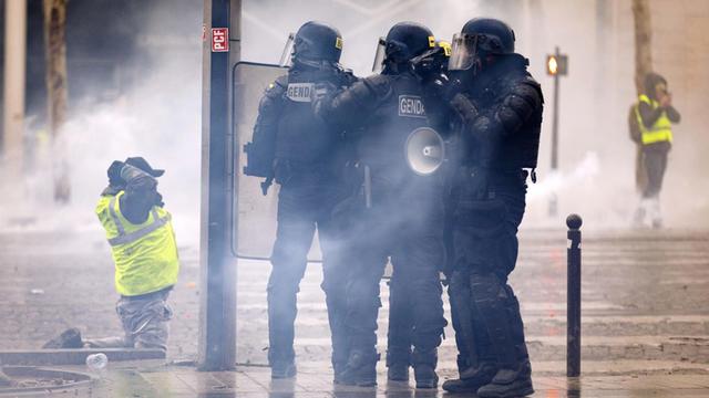 Polizisten und Demonstranten der Gelbwesten-Bewegung stehen sich in Paris gegenüber.