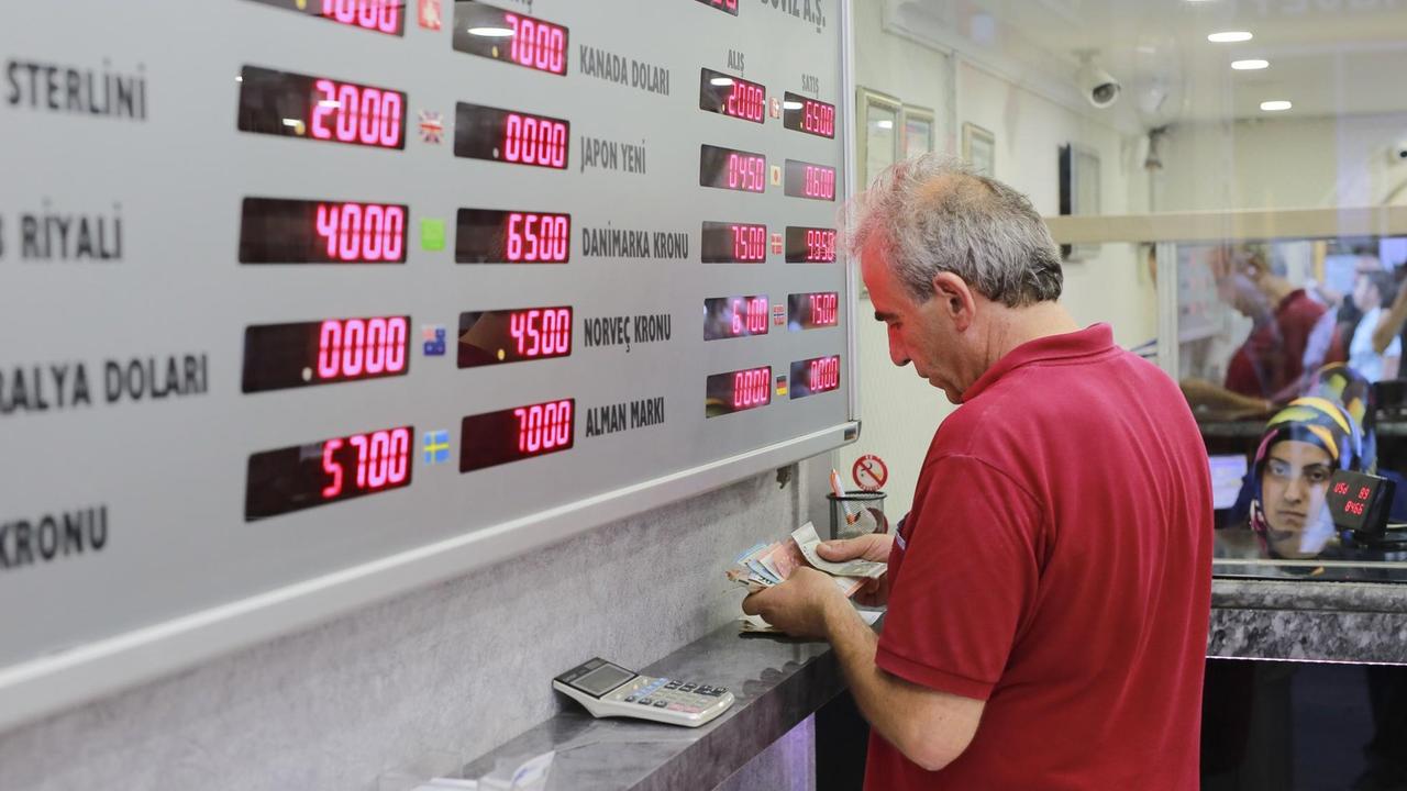 Ein Mann zählt vor einer Anzeigetafel mit Währungskursen seine türkischen Lira in einer Wechselstube in Ankara.