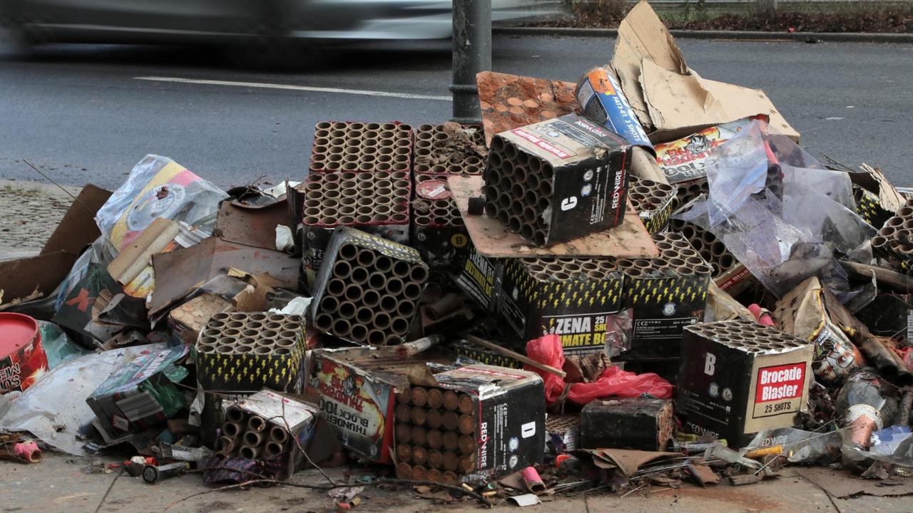 Die Reste abgebrannter Silvesterknaller und große leere Böller-Batterien (Müll) liegen am Neujahrsmorgen zusammengefegt am Straßenrand in einer Starße in Berlin