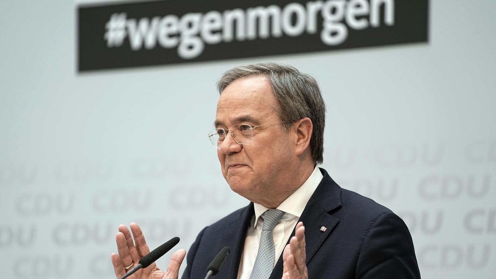 Laschet gestikuliert vor einem Mikrofon. Hinter ihm an der Wand prangt der Hashtag #wegenmorgen. Laschet gestikuliert vor einem Mikrofon. Hinter ihm an der Wand prangt der Hashtag #wegenmorgen.