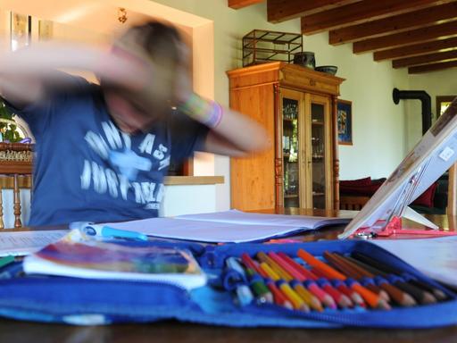 Ein zehnjähriger Junge hält und schüttelt am 02.04.2011 in Arnsberg (Nordrhein-Westfalen) beim erledigen seiner Hausaufgaben seinen Kopf.