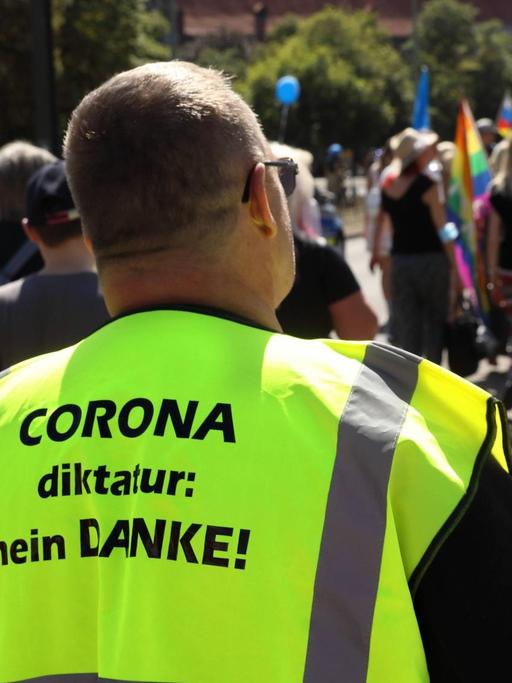 Auf der neongelben Jacke eines Demonstranten steht: "Corona-Diktatur Nein Danke".