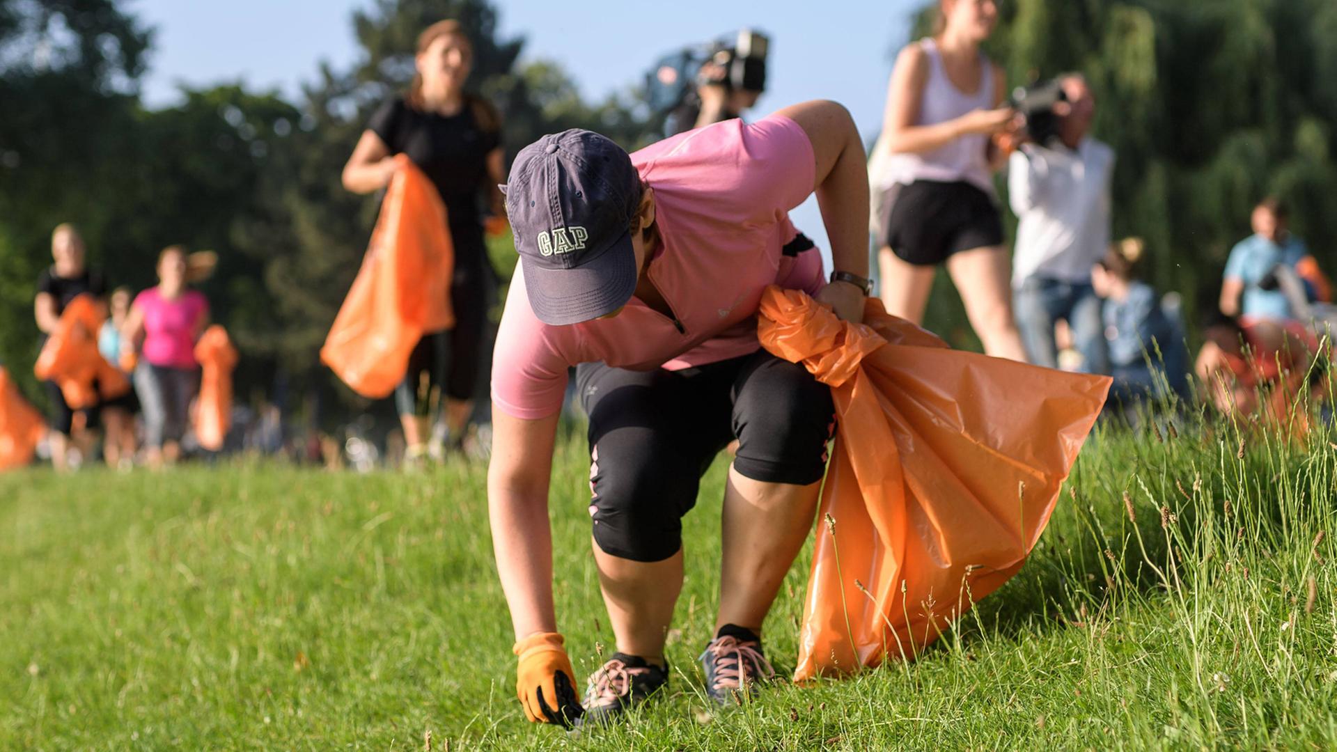 Plogging Lauf in Köln am Weltumwelttag am 5. Juni 2018 sammeln Müll in einem Park in orangenen Plastiktüten Plogging Lauf in Köln am Weltumwelttag am 5. Juni 2018 sammeln Müll in einem Park in orangenen Plastiktüten