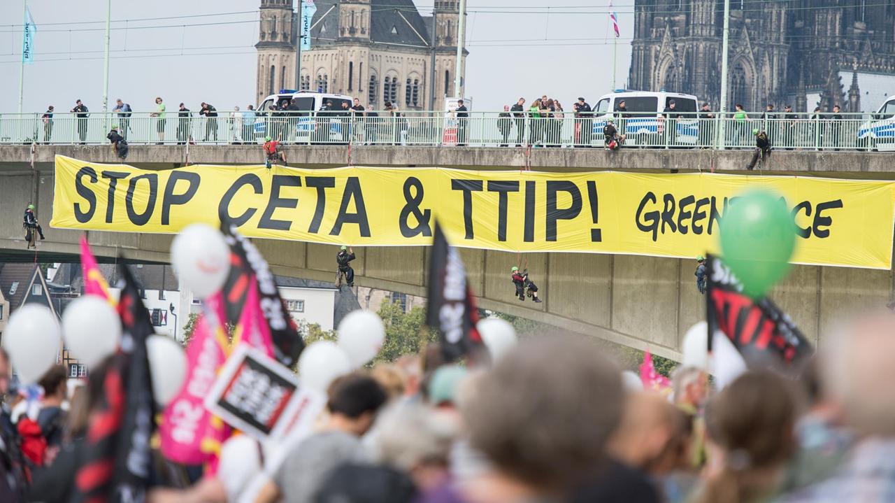 Aktivisten von Greanpeace bringen ein Banner an der Deutzer Brücke an am 17.09.2016, bei einer Demonstration gegen die Handelsabkommen CETA und TTIP in Köln (Nordrhein-Westfalen). Aktivisten von Greanpeace bringen ein Banner an der Deutzer Brücke an am 17.09.2016, bei einer Demonstration gegen die Handelsabkommen CETA und TTIP in Köln (Nordrhein-Westfalen).