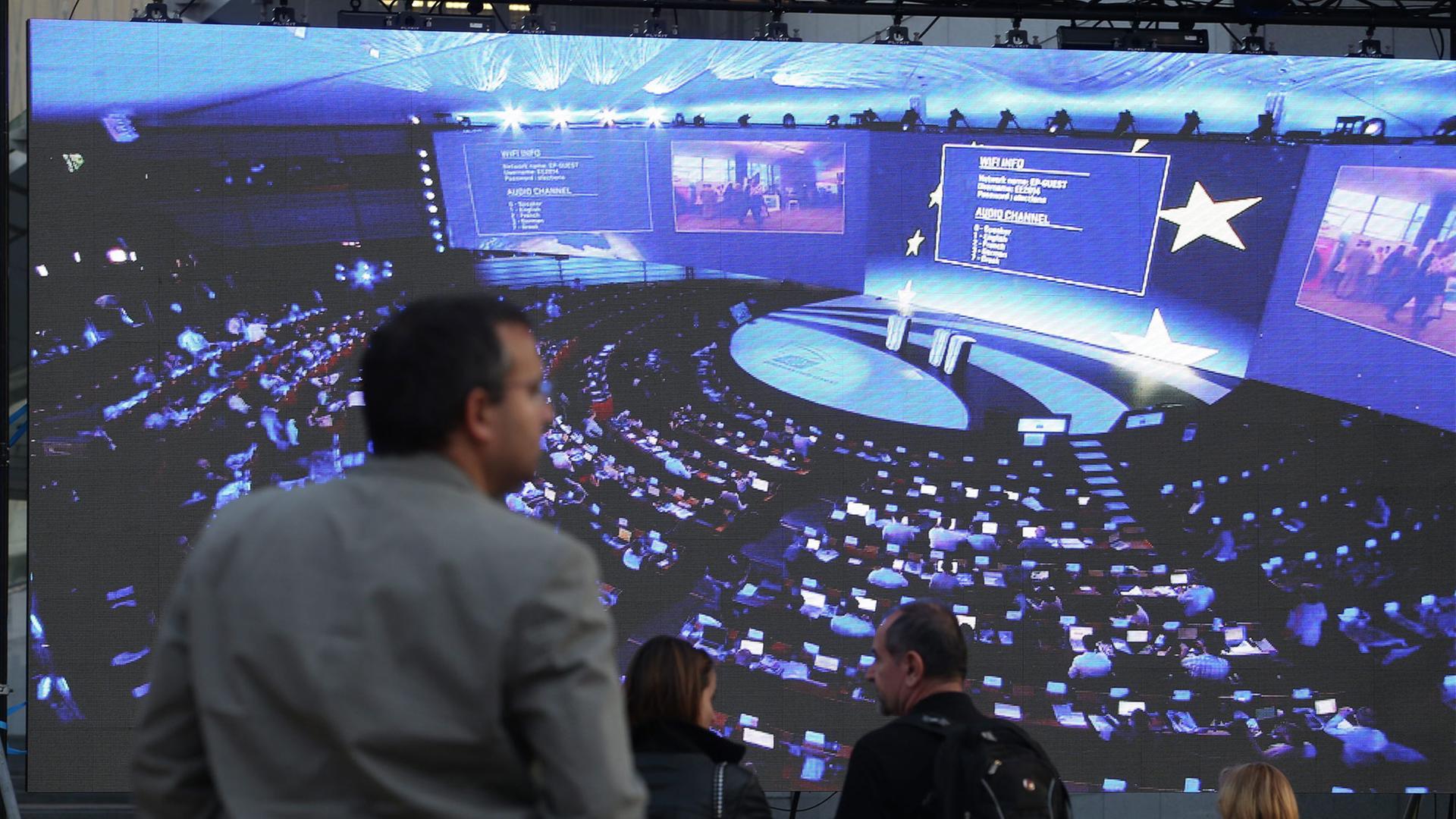 Zuschauer warten in Brüssel vor einer Videoleinwand, die Bilder aus dem Europäischen Parlament überträgt, auf die Ergebnisse der Europa-Wahl 2014. Zuschauer warten in Brüssel vor einer Videoleinwand, die Bilder aus dem Europäischen Parlament überträgt, auf die Ergebnisse der Europa-Wahl 2014.