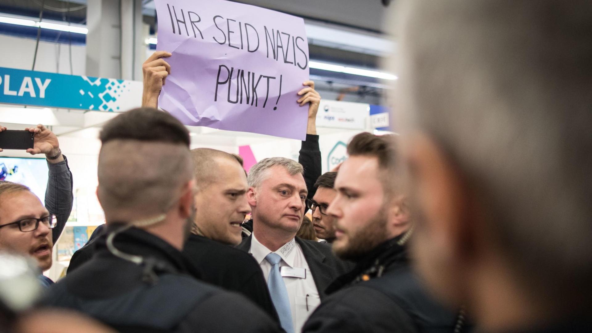 Ein Demonstrant hält ein Protestplakate mit der Aufschrift "Ihr seid Nazis Punkt!" hoch. Ein Demonstrant hält ein Protestplakate mit der Aufschrift "Ihr seid Nazis Punkt!" hoch.