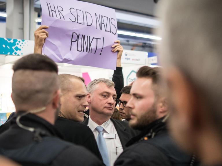 Ein Demonstrant hält ein Protestplakate mit der Aufschrift "Ihr seid Nazis Punkt!" hoch.