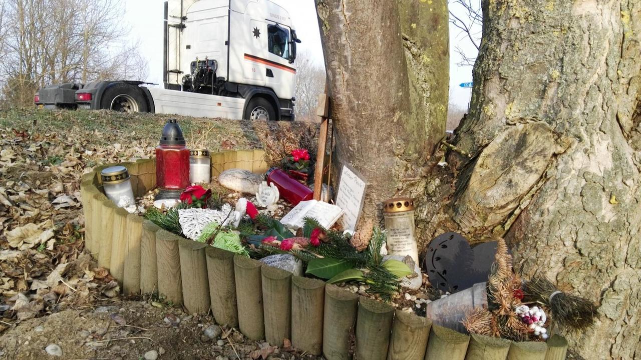 An einem Baum auf einem Parkplatz sind Blumen und Grablichter abgelegt, die an den Fall Patrick H. erinnern.