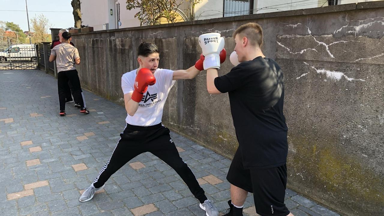 Mehrere Jungs des Boxclubs Lübeck trainieren auf der Straße aus dem Pflaster neben einer Mauer.