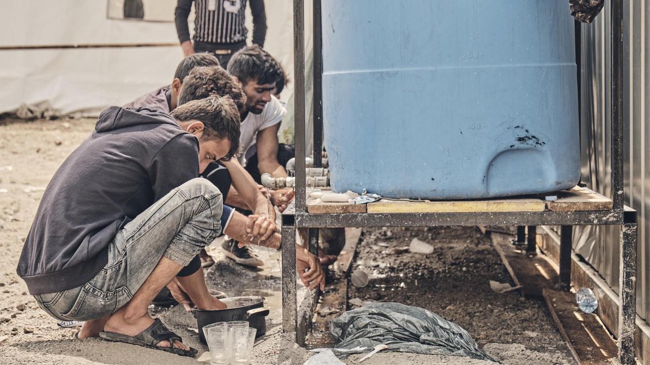 Männer waschen sich an einem Wassertank. Es gibt vier Tanks im Flüchtlingslager - für bis zu 700 Menschen. Männer waschen sich an einem Wassertank. Es gibt vier Tanks im Flüchtlingslager - für bis zu 700 Menschen.