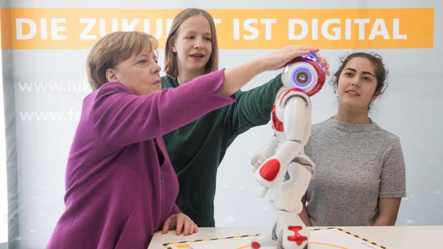 Bundeskanzlerin Angela Merkel (CDU) macht bei der Auftaktveranstaltung zum Girls Day am Stand des Fraunhofer-Instituts Bekanntschaft mit dem Roboter Nao am 25.04.2018