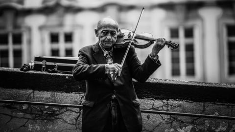 Ein älterer Mann spielt Geige auf der Straße.