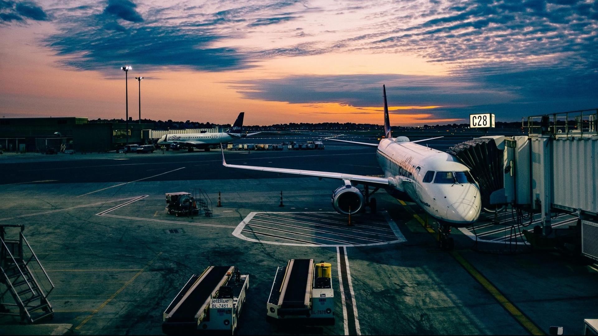Der Flughafen von Boston im Abendlicht. Ein Flugzeug parkt an einem Eingang zum Gate. Der Flughafen von Boston im Abendlicht. Ein Flugzeug parkt an einem Eingang zum Gate.