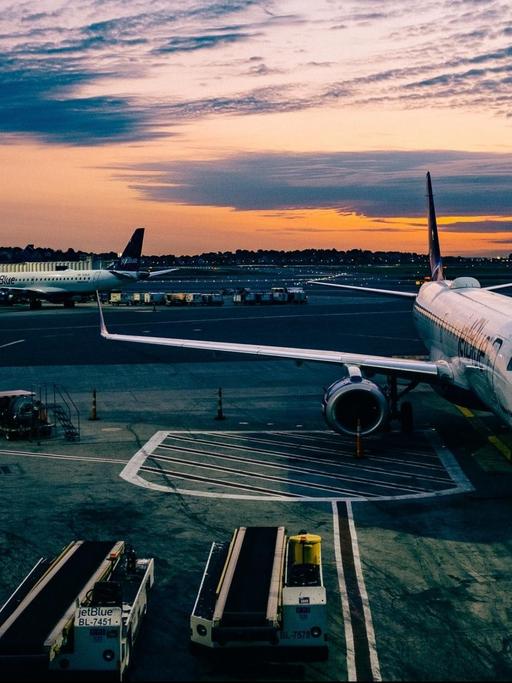 Der Flughafen von Boston im Abendlicht. Ein Flugzeug parkt an einem Eingang zum Gate.