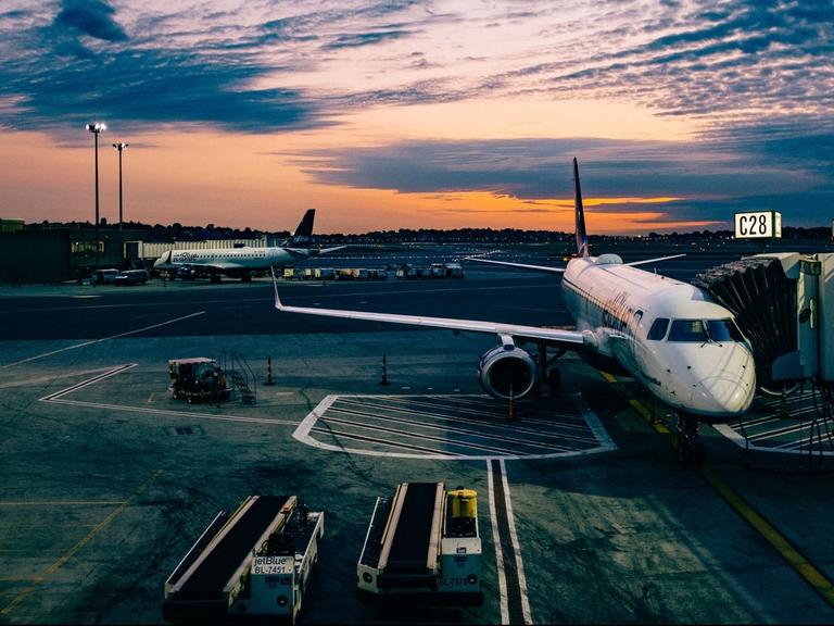 Der Flughafen von Boston im Abendlicht. Ein Flugzeug parkt an einem Eingang zum Gate.
