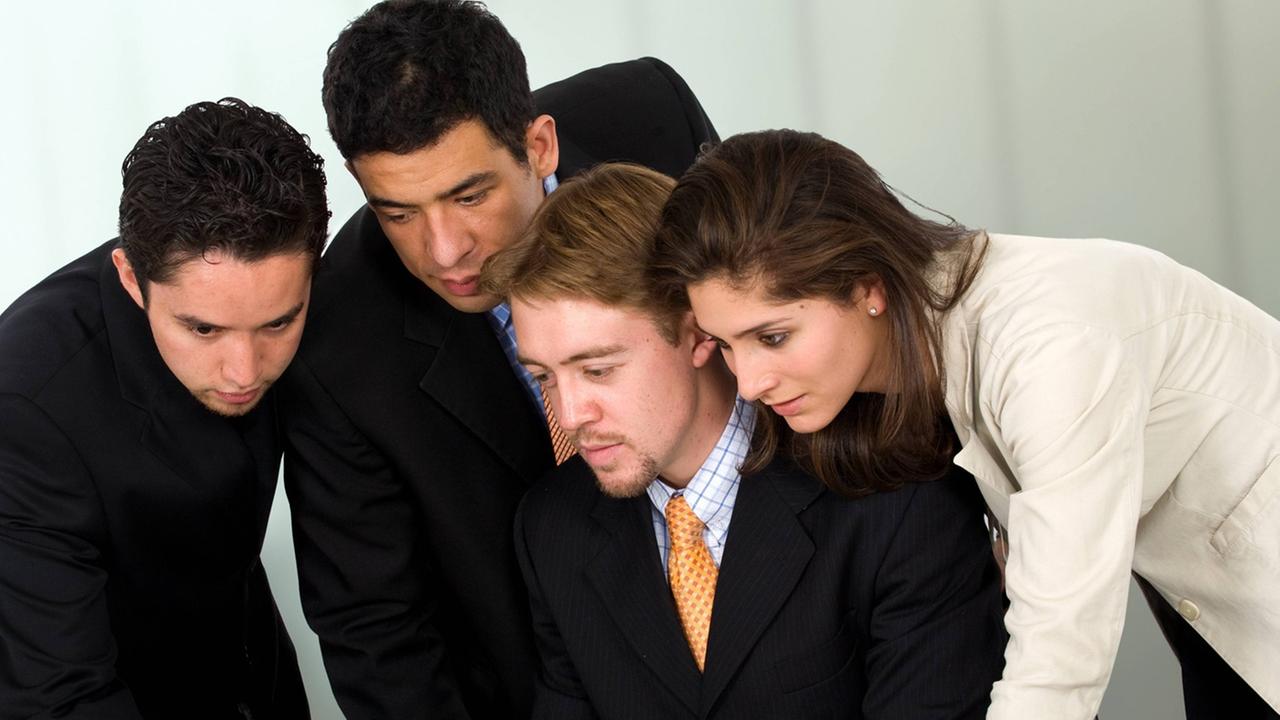 Ein Mann und eine Frau in Business-Look beugen sich gemeinsam über einen Laptop-Computer Ein Mann und eine Frau in Business-Look beugen sich gemeinsam über einen Laptop-Computer