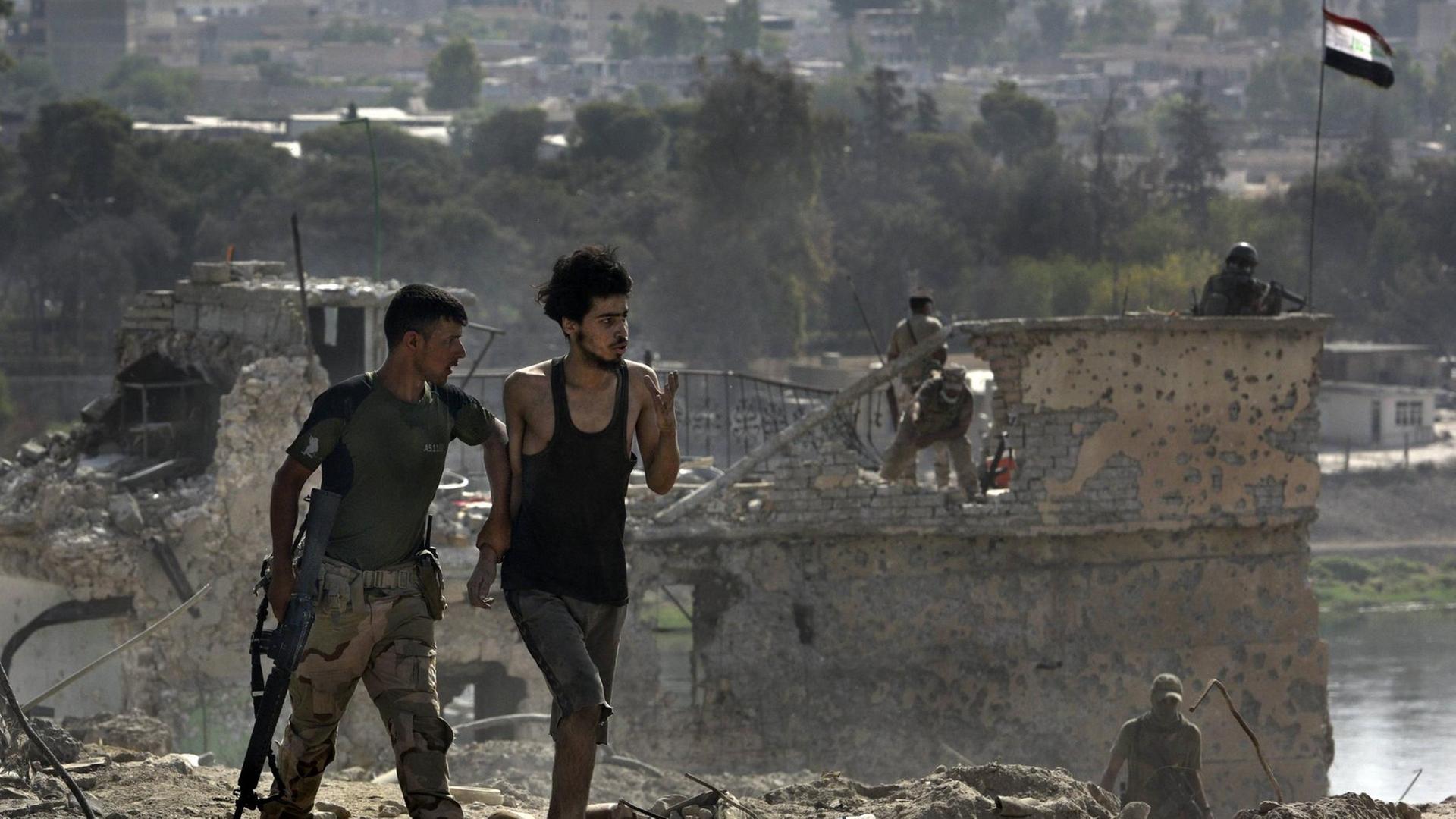 July 18, 2017. Mosul, Iraq: ISIS fighter is led away after surrendering to Iraqi Army soldiers on July 18, 2017 amid ruins of the Old City.