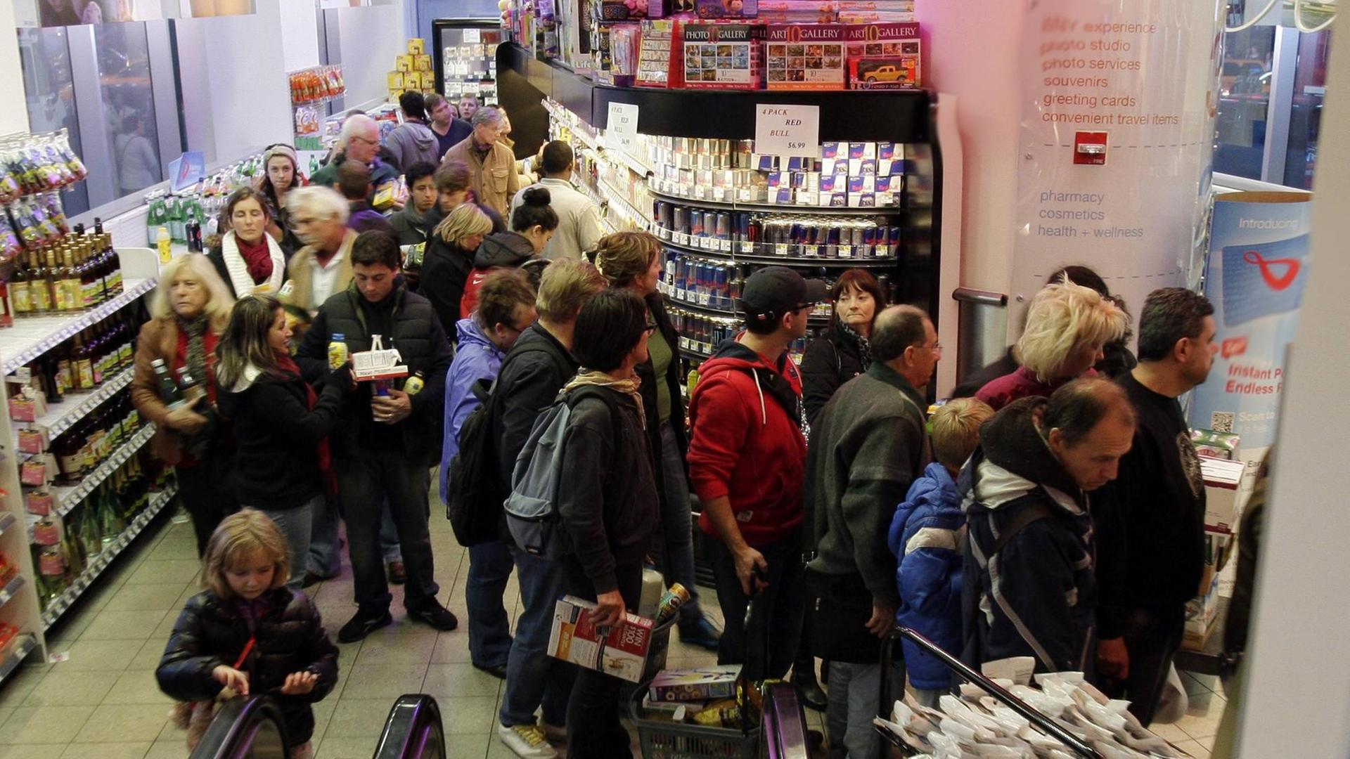 Eine Menschenmenge steht in einer langen Schlange in einem Supermarkt vor der Kasse Eine Menschenmenge steht in einer langen Schlange in einem Supermarkt vor der Kasse