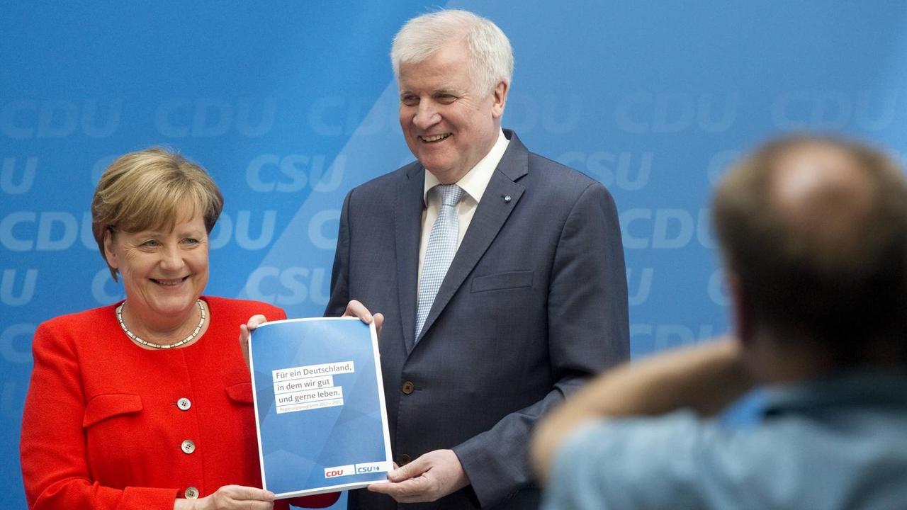 Merkel und Seehofer mit Parteigrogramm vor Kameras