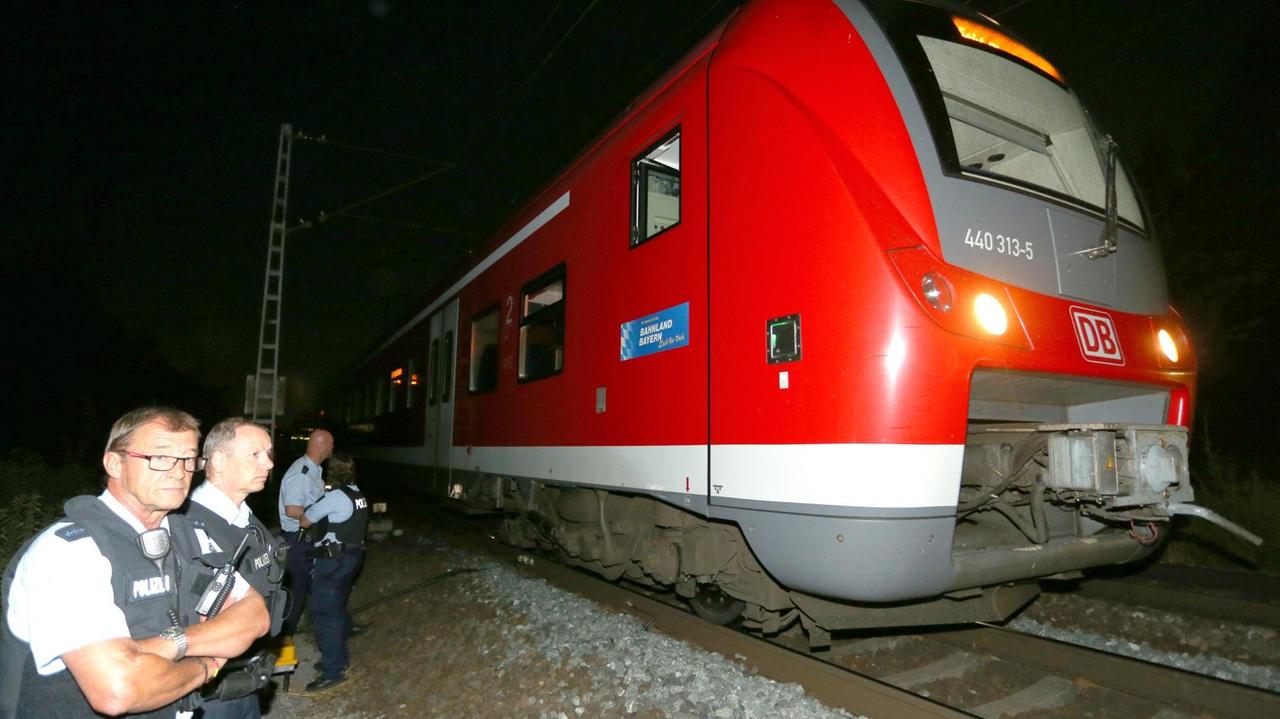 Polizisten stehen am 18.07.2016 bei Würzburg neben dem Zug, in dem ein 17-jähriger Asylbewerber mehrere Reisende mit einem Beil und einem Messer angriff und verletzte Polizisten stehen am 18.07.2016 bei Würzburg neben dem Zug, in dem ein 17-jähriger Asylbewerber mehrere Reisende mit einem Beil und einem Messer angriff und verletzte