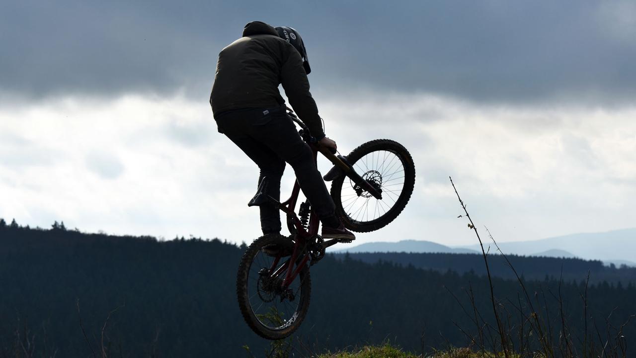 Ein Mountainbiker springt am 26.10.2017 auf dem Ettelsberg in Willingen (Hessen) über eine Kuppe. Nahe der Bikestrecke wird die Bergstation des neuen Sessellifts entstehen. Mit dem mit knapp 1500 Metern längsten Sessellift Hessens will das Wintersportgebiet seine Stellung als Skiressort im Sauerland ausbauen. Fertiggestellt werden soll er im Herbst 2018. Foto: Uwe Zucchi/dpa | Verwendung weltweit Ein Mountainbiker springt am 26.10.2017 auf dem Ettelsberg in Willingen (Hessen) über eine Kuppe. Nahe der Bikestrecke wird die Bergstation des neuen Sessellifts entstehen. Mit dem mit knapp 1500 Metern längsten Sessellift Hessens will das Wintersportgebiet seine Stellung als Skiressort im Sauerland ausbauen. Fertiggestellt werden soll er im Herbst 2018. Foto: Uwe Zucchi/dpa | Verwendung weltweit