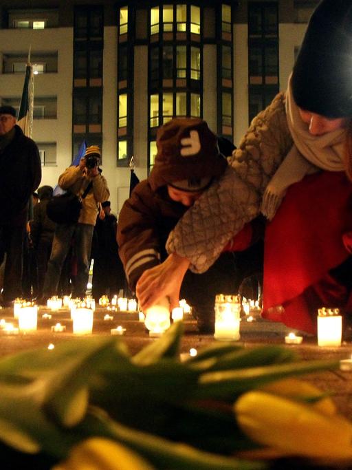 Menschen stellen Kerzen für die Todesopfer von Mariupol in der Ukraine auf und legen Blumen nieder.