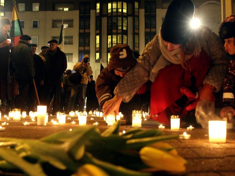 Menschen stellen Kerzen für die Todesopfer von Mariupol in der Ukraine auf und legen Blumen nieder.