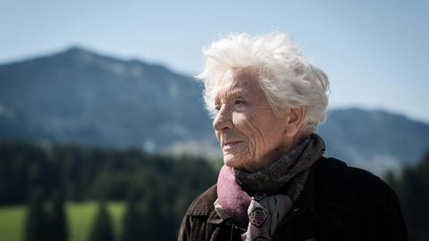 Porträt von Annette Beaumanoir in einer bergigen Landschaft.