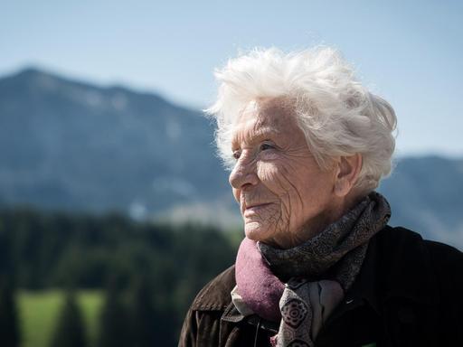 Porträt von Annette Beaumanoir in einer bergigen Landschaft.