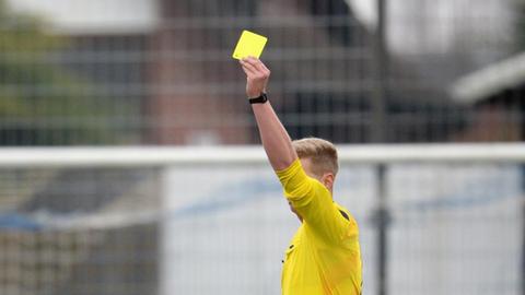 Der Schiedsrichter zeigt am 14.03.2015 bei einem Fußballspiel in eine gelbe Karte.