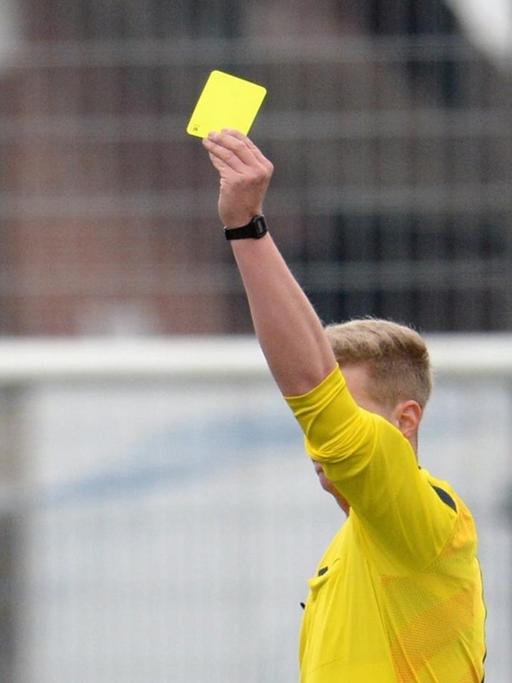 Der Schiedsrichter zeigt am 14.03.2015 bei einem Fußballspiel in eine gelbe Karte.