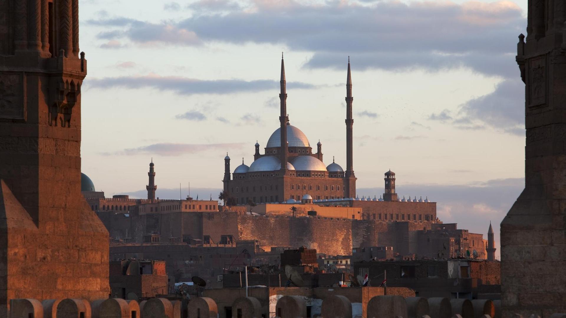 Blick vom Dach der Mu'ayyad Moschee durch die über dem Stadttor Bab Zuweila aufragenden Minarette auf die Zitadelle mit Kairos Wahrzeichen, der Mohammed Ali Moschee. Blick vom Dach der Mu'ayyad Moschee durch die über dem Stadttor Bab Zuweila aufragenden Minarette auf die Zitadelle mit Kairos Wahrzeichen, der Mohammed Ali Moschee.