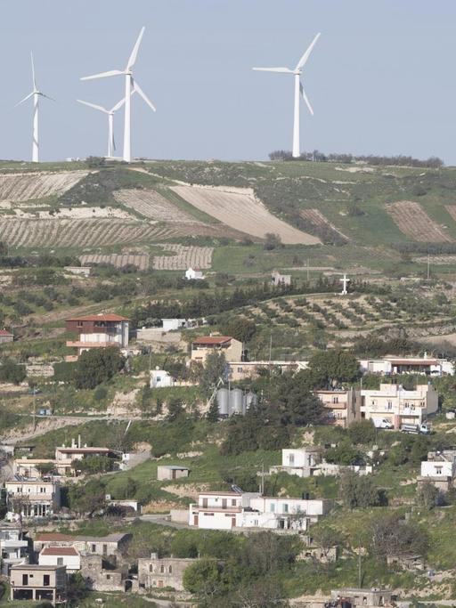 Windräder stehen über einem Bergdorf auf Kreta.