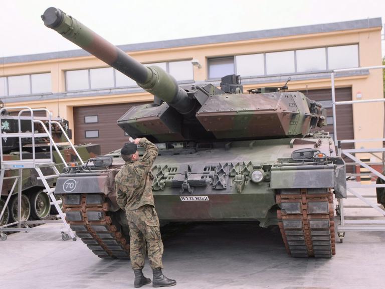 Ein Soldat begutachtet einen deutschen Leopard-Panzer.
