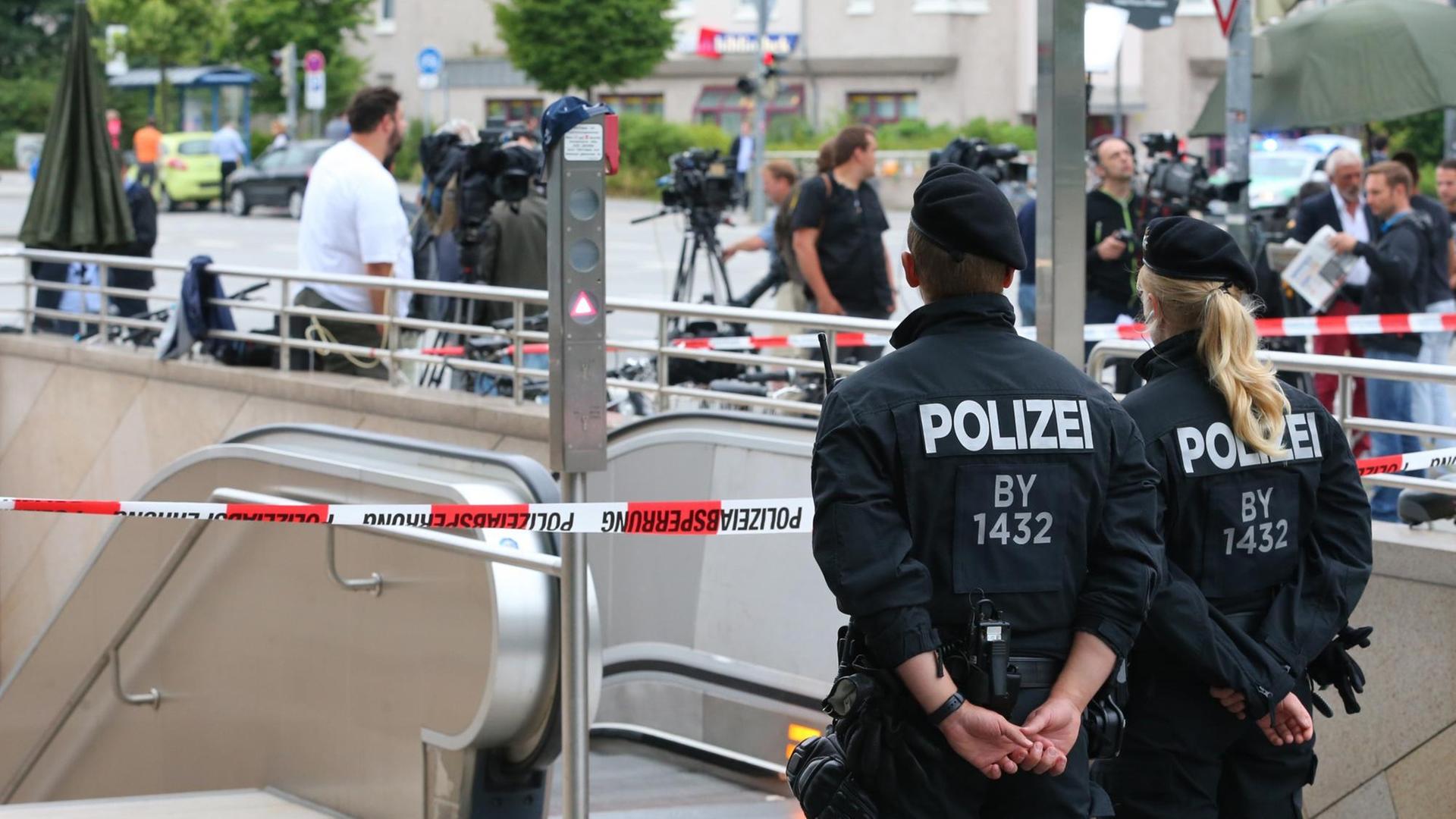 Sie sehen Polizisten und ein Absperrband am Eingang zur U-Bahnstation Olympia-Einkaufszentrum. Sie sehen Polizisten und ein Absperrband am Eingang zur U-Bahnstation Olympia-Einkaufszentrum.