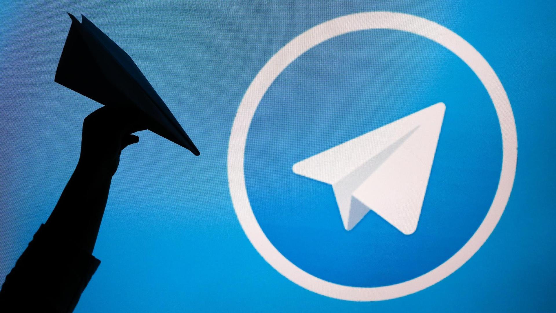 Telegram-Symbol neben Hand, die einen Papierflieger hochhält