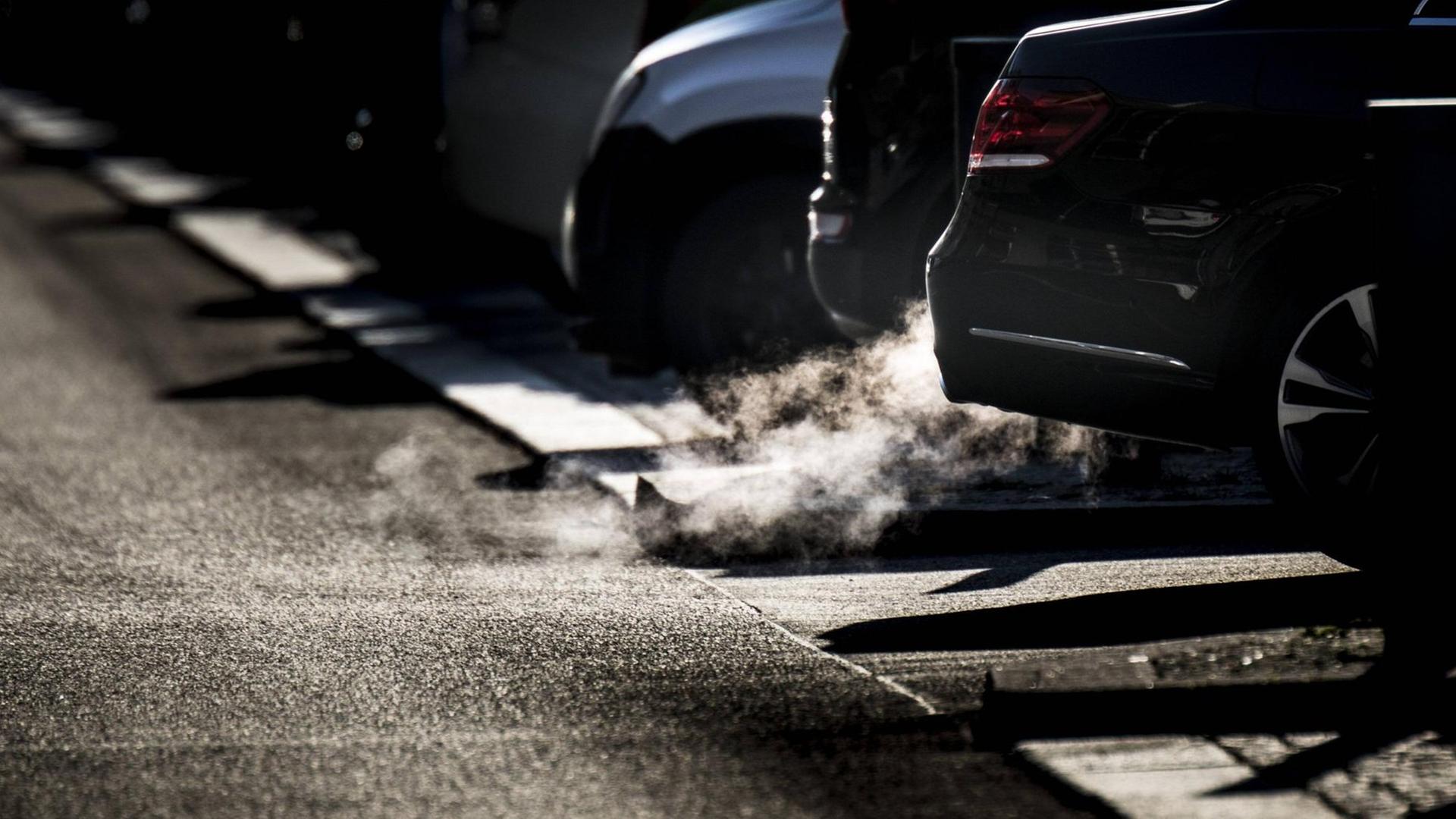 Abgase entweichen im Gegenlicht aus dem Auspuff von Autos. Abgase entweichen im Gegenlicht aus dem Auspuff von Autos.