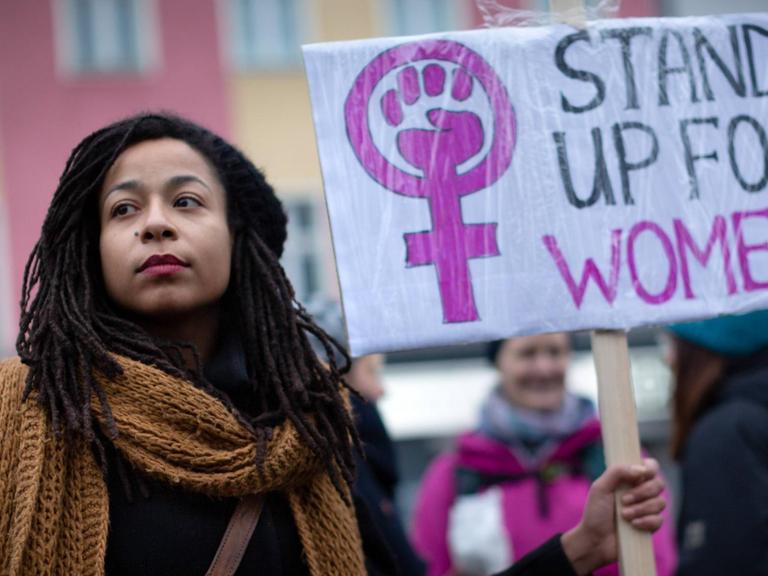 Das Foto zeigt eine junge Demonstrantin auf dem internationalen Frauentag vom 8. März 2019. Sie hält ein Schild mit der Aufschrift: "Stand up for women"