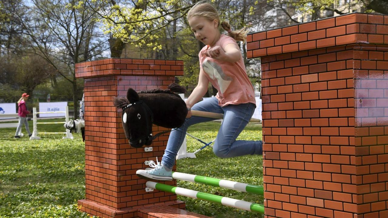 Ein Mädchen springt mit seinem Steckenpferd über ein Hindernis bei einem "Hobby Horsing"-Turnier in Helsinki. Ein Mädchen springt mit seinem Steckenpferd über ein Hindernis bei einem "Hobby Horsing"-Turnier in Helsinki.