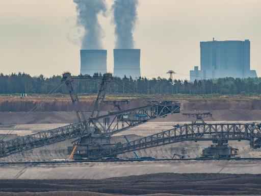 Ein Schaufelradbagger steht im Braunkohletagebau Welzow-Süd der Lausitz Energie Bergbau AG (LEAG). Dahinter steigt Wasserdampf aus den Kühltürmen des Braunkohlekraftwerkes Schwarze Pumpe.