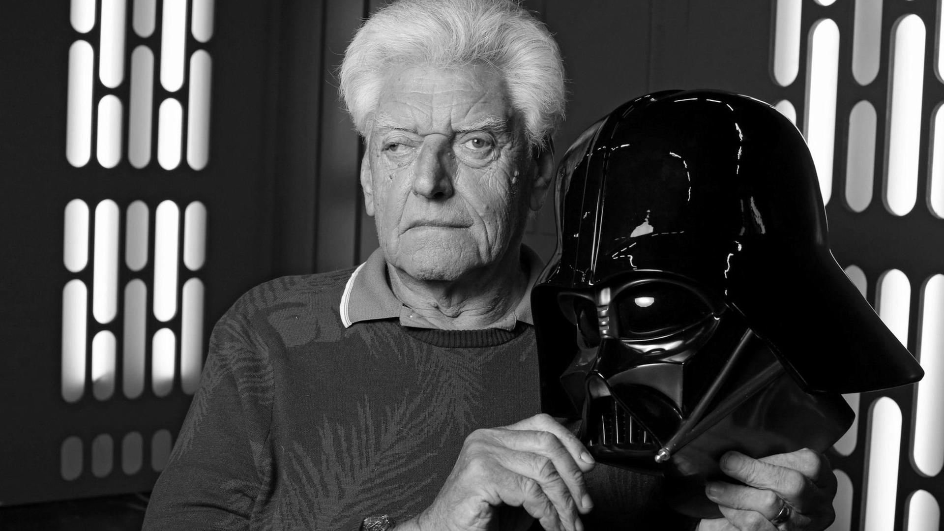 Der Schau-Spieler David Prowse mit der Maske von seinem schwarzen Darth-Vader-Kostüm in der Hand Der Schau-Spieler David Prowse mit der Maske von seinem schwarzen Darth-Vader-Kostüm in der Hand