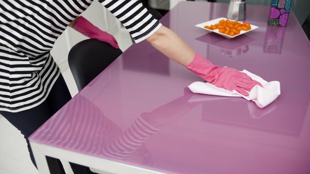 Putzende Frau am Küchentisch