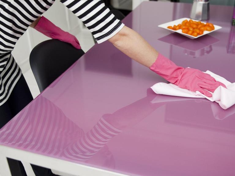 Putzende Frau am Küchentisch