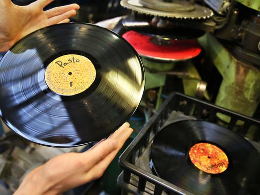 Ein Mitarbeiter eines Plattenlabels prüft eine frisch gepresste Schallplatte in einem Presswerk.