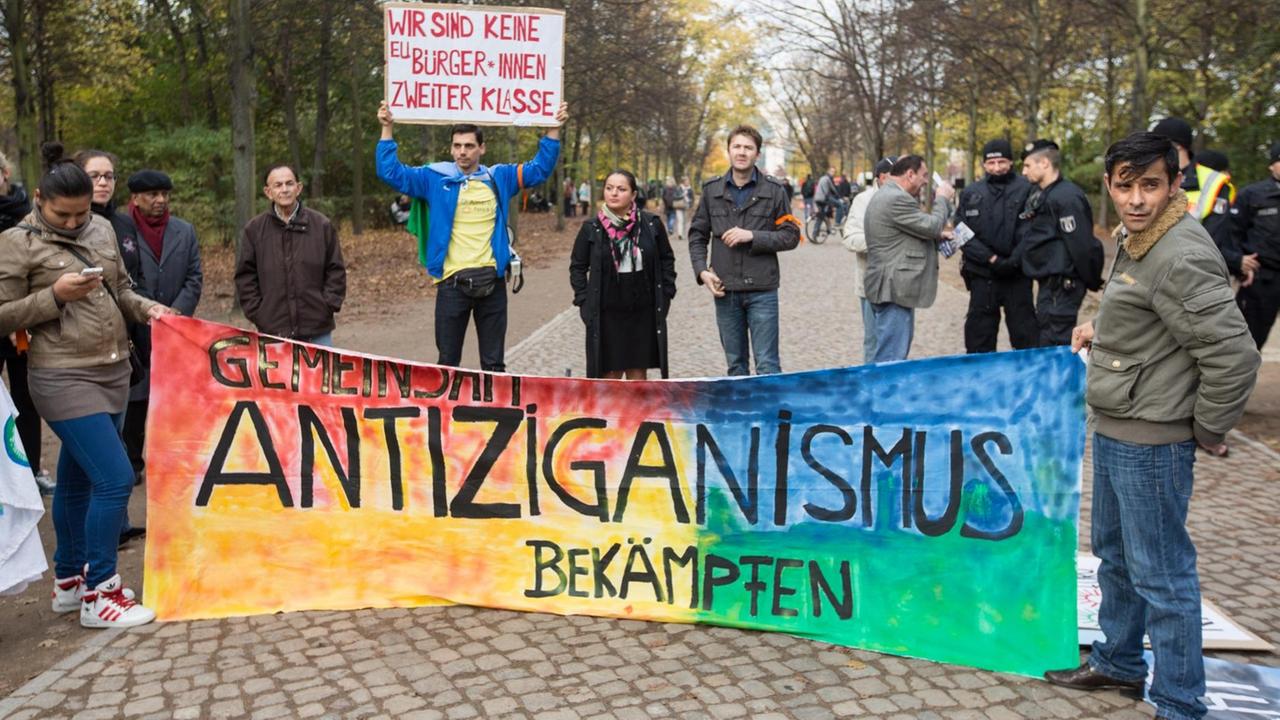 Gemeinsam Antiziganismus bekämpfen" steht vor dem Mahnmal für Sinti und Roma in Berlin bei einer Kundgebung auf einem Banner.