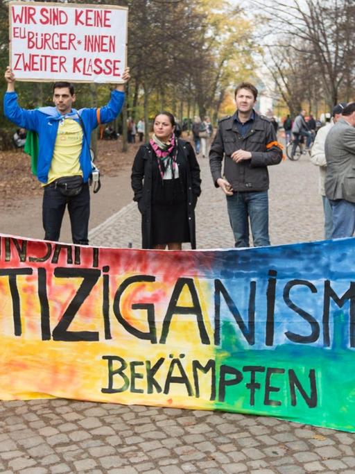Gemeinsam Antiziganismus bekämpfen" steht vor dem Mahnmal für Sinti und Roma in Berlin bei einer Kundgebung auf einem Banner.