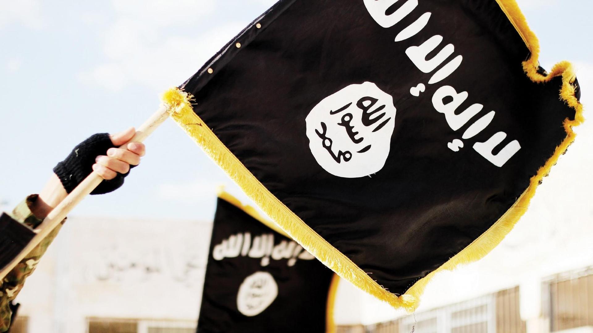 Eine schwarze Flagge mit dem Logo der Terrormiliz Islamischer Staat. Eine schwarze Flagge mit dem Logo der Terrormiliz Islamischer Staat.