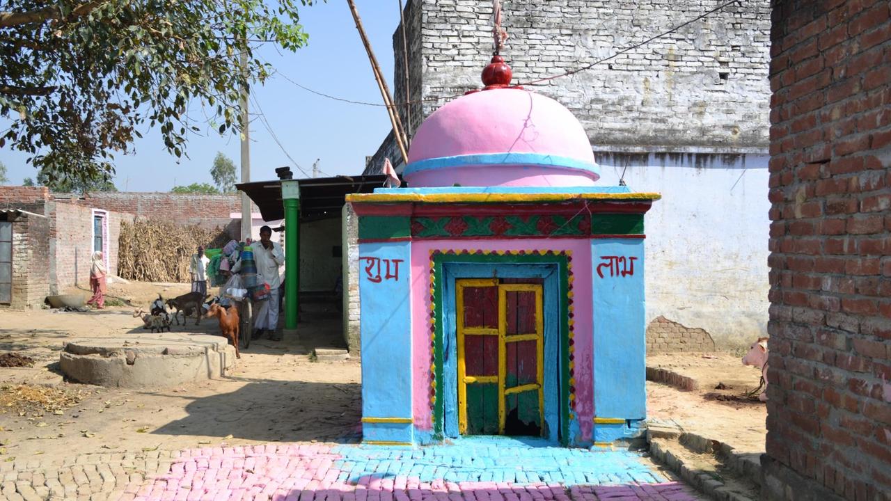 Rosa-blauer Tempel auf einem Dorfplatz in Indien