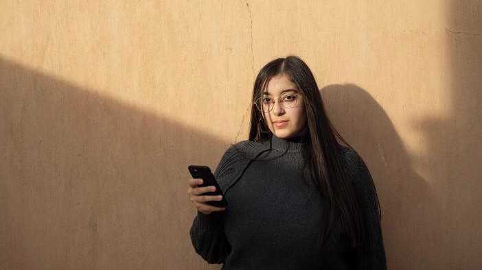 Studentin Zeina Amr hilft Frauen in Ägypten über das Internet auf ihrer Seite "Cat Calls Cairo" sich gegen sexualisierte Gewalt zu wehren. Sie steht vor einer Wand mit dem Handy in der Hand.